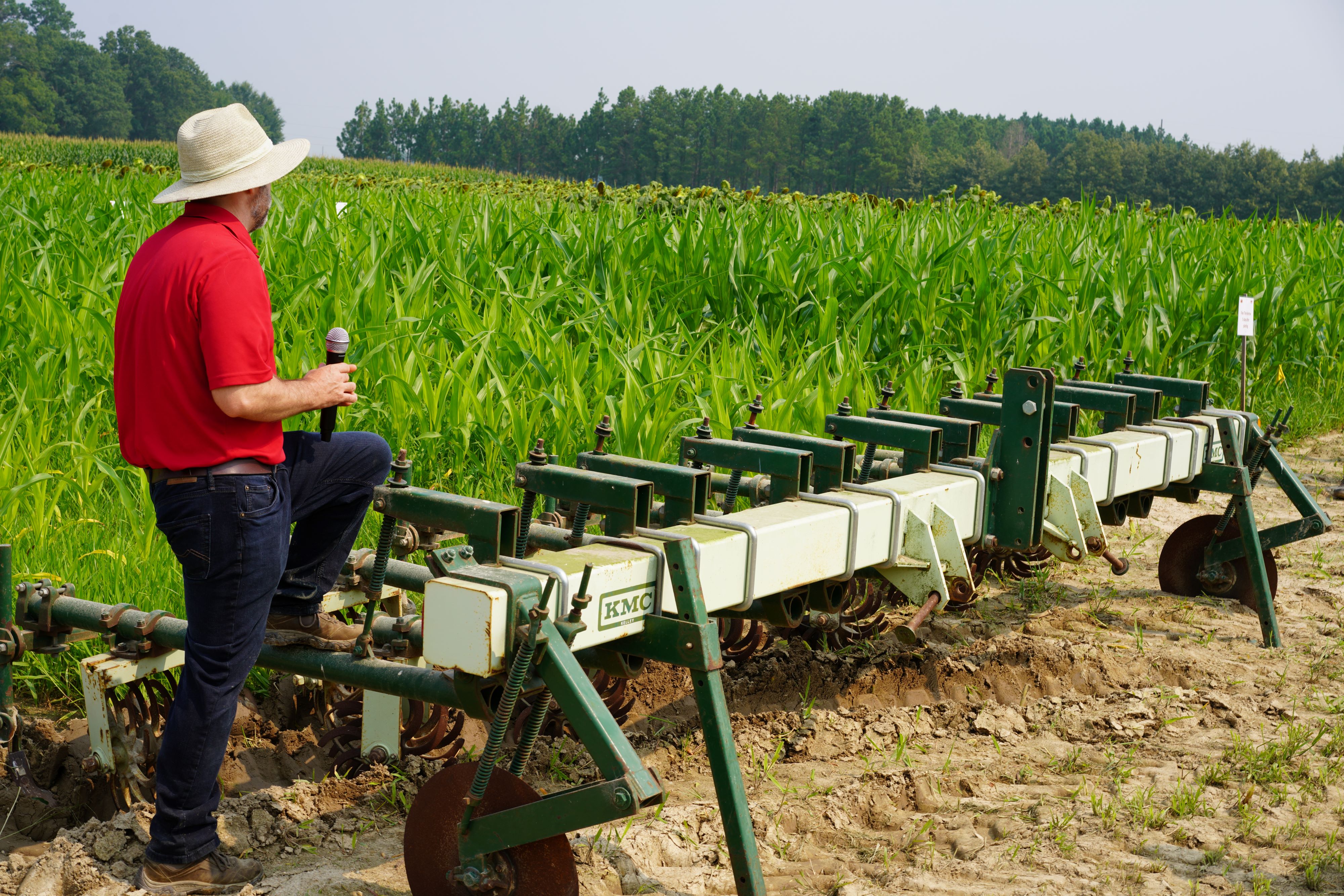 A man discusses farm equipment in a field.